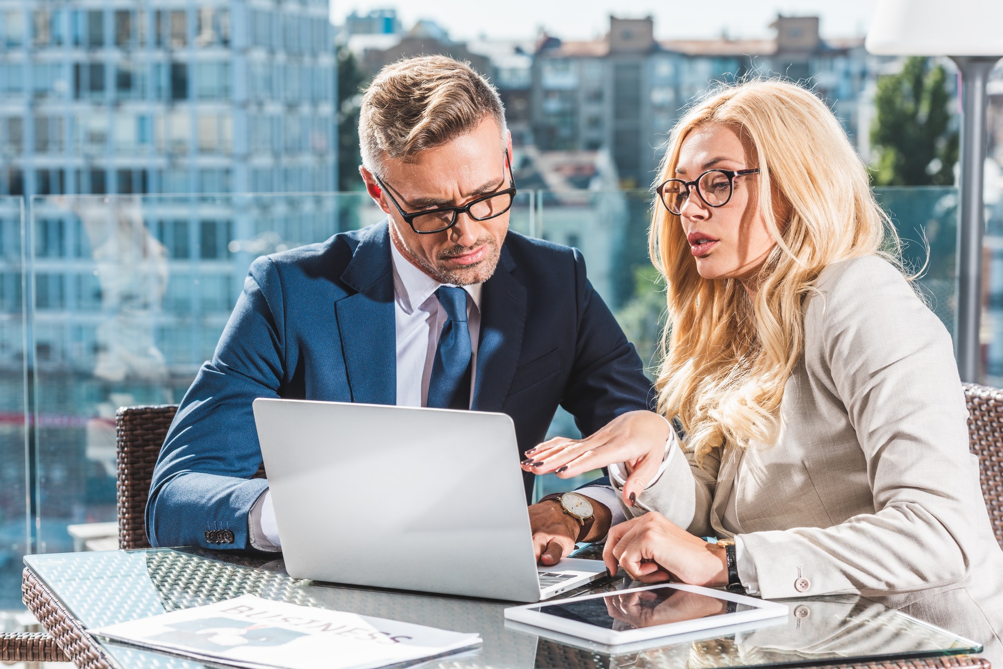 confident business colleagues using laptop during business meeting in cafe